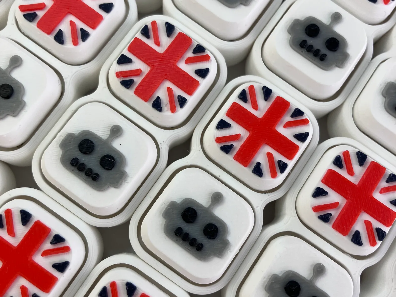 Close up of white Twin clickers with robot and Union Jack caps, packed side by side